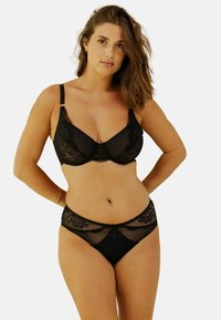 Ensemble de bralette et culotte en dentelle noire assortie. Comprend des panneaux transparents, des accents en dentelle florale, des fines bretelles et un petit nœud décoratif au centre.