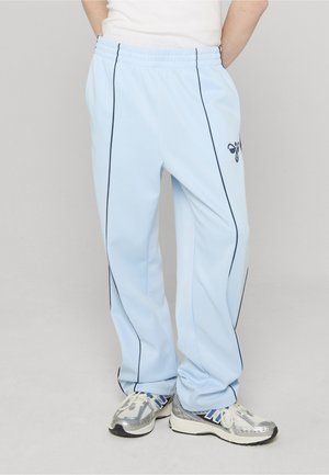 Jasnoniebieskie spodnie dresowe z ciemnoniebieskimi paskami po bokach i elastycznym pasem. Wykonane z miękkiego materiału. Posiadają małe logo w okolicy biodra.