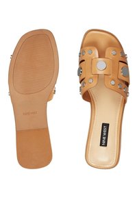 Sandales plates marron clair avec bouts carrés, clous argentés sur des brides larges, et étiquette "Nine West" sur la semelle intérieure.