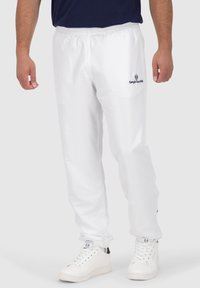 Weiße, leichte Sporthose mit einem elastischen Bund. Mit Seitentaschen und einem kleinen blauen Logo am linken Oberschenkel.