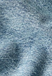 Jasnoniebieska tkanina dżinsowa o strukturze tkaniny, ukazująca subtelne różnice w kolorze oraz miękką i elastyczną jakość.