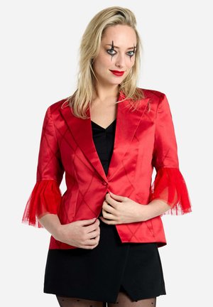 Rdeč satenski blazer z oblikovano zasnovo, rokavi do tri četrtine, ki vsebujejo tulle volančke, in zapiranje z enim gumbom. Črna bluzica spodaj.