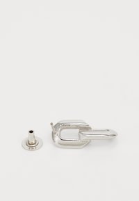 Chiusura per orecchini in metallo argentato con un design a forma di gancio. Presenta una finitura lucida e un dettaglio con logo inciso sul pezzo più grande.