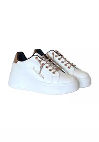 Sneaker bianche con una piattaforma chunky, accenti marroni e dettagli metallici per i lacci. Presentano una texture liscia simile alla pelle e un dettaglio del logo.