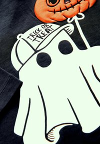 Schwarzes T-Shirt mit einem weißen Geistergrafik-Design mit schwarzen Akzenten, einem Kürbis-Luftballon und dem Text "TRICK OR TREAT" auf einer Kappe.