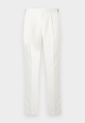 Pantaloni bianchi su misura con pieghe frontali e linguette regolabili laterali, appesi contro uno sfondo semplice.