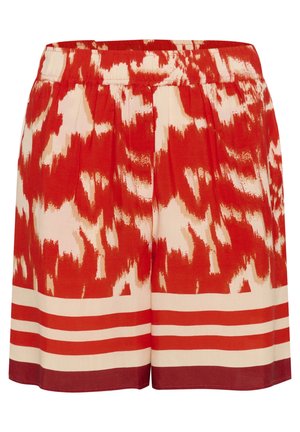 Röda och krämfärgade mönstrade shorts med elastisk midja. Har abstrakta mönster och horisontella ränder nära fållen. Mjuk tygtextur.