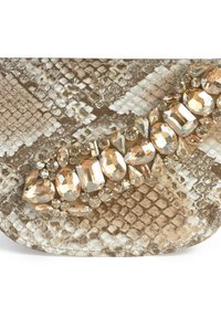 Płaskie buty w wzór wężowej skóry z beżowymi i złotymi akcentami, z pasem dużych, oszlifowanych cyrkonii oraz różnorodnymi kształtami ozdób.