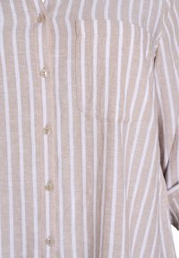 Camicia button-up in lino beige con righe verticali bianche. Presenta una tasca sul petto, orlo arrotondato e bottoni di colore naturale.