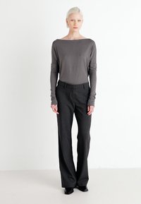 Grey long-sleeve top with boat neckline, paired with black, high-waisted, wide-leg trousers. Smooth fabric and tailored fit. Minimalist design.