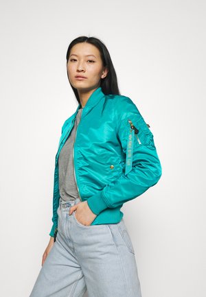 Teal bomber jacket made of shiny fabric, featuring a relaxed fit, zippered pockets, ribbed cuffs, and a woven accent on the sleeve.