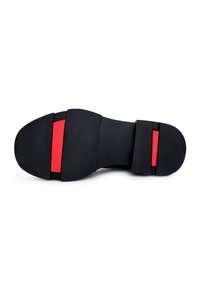Semelle de chaussure noire avec une surface antidérapante texturée présentant deux accents rectangulaires rouges, l'un près du talon et l'autre près de l'orteil.