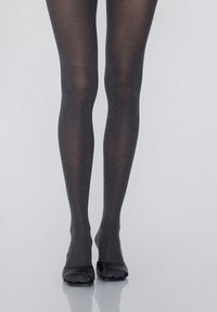 Collants noirs opaques avec un léger éclat, présentant une texture douce et associés à des chaussures noires à bout ouvert.