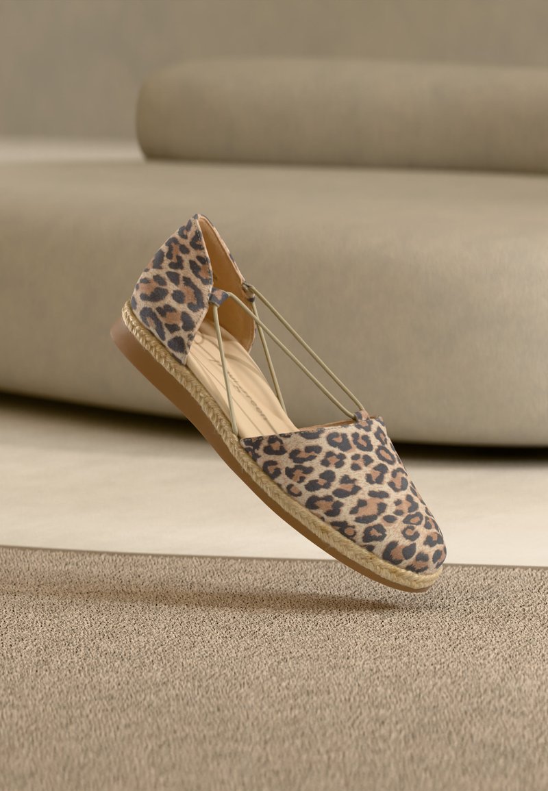 Εσπαντρίγια με φλατ σόλα και τύπωμα λεοπάρ, με μπεζ ελαστικούς ιμάντες και πλεγμένη σόλα από τζούτ, σε φόντο μπεζ χαλί και καναπέ.