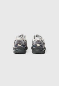 Pair of gray and black athletic shoes with "GEL" branding on the heel, viewed from the back against a plain light background.
