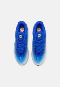 Paire de baskets Nike Air Max bleues avec des détails en dégradé blanc et des logos Swoosh noirs, vues de dessus sur un fond blanc.
