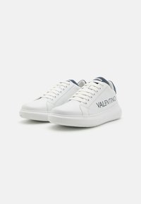 Fehér bőr sneakers sötétkék részletekkel, kerek orral, lapos fűzőkkel és a "VALENTINO" logóval az oldalán. Vastag gumi talp, sima textúra.