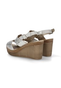 Sandalias de cuña plateadas con una plataforma texturizada de color marrón claro. Cuentan con correas entrecruzadas y correas ajustables en el tobillo para un ajuste seguro.