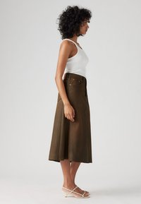 Falda marrón, hasta la rodilla, con una silueta recta, hecha de una tela suave. Presenta bolsillos delanteros y un detalle de botones en la cintura.