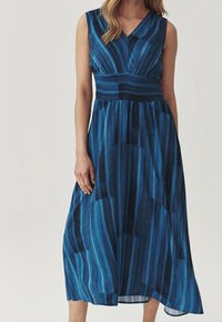 Ärmlös blå klänning med V-ringning, smockad midja och A-linjeform; har vertikala ränder och en mjuk tygtextur.