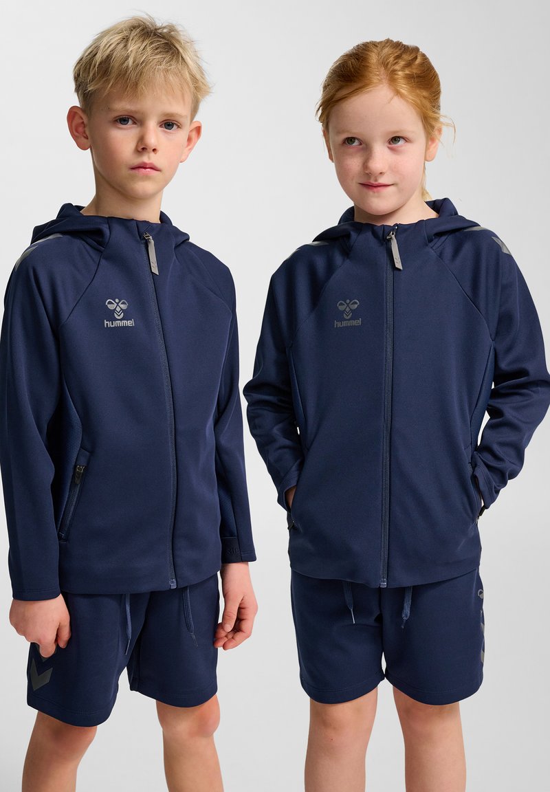 Mörkblå sportjackor med huvor, dragkedja framtill och sidofickor; matchade med matchande shorts med logotyp och mönstrade detaljer.