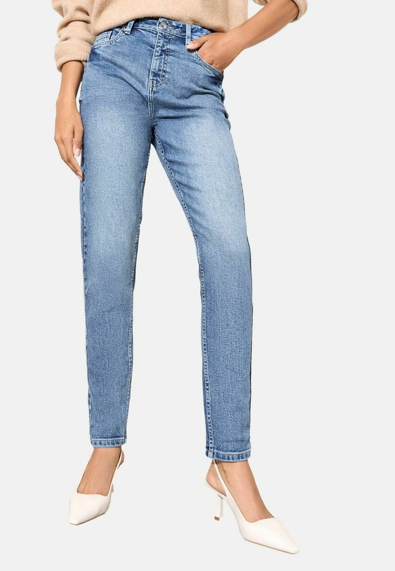 Svetlo modré džínsy s vysokým pásom, ktoré majú klasický dizajn s piatimi vreckami, štíhly strih a jemné vyblednutie. Skombinované s bielymi lodičkami s ostrou špičkou.