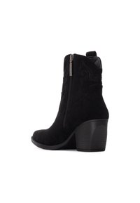 Botas de tobillo de ante negro con cremallera lateral, tacón apilado y detalle de costura decorativa. Textura suave y diseño de punta redonda.