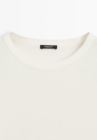 Weißes T-Shirt mit Rundhalsausschnitt und einem schwarzen Massimo Dutti-Label, das innen am Kragen eingenäht ist, hergestellt in Indien.