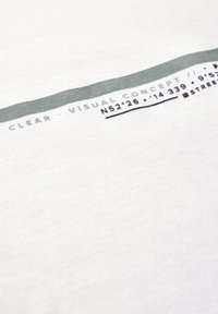 White cotton T-shirt featuring a horizontal gray stripe with printed text and coordinates, showcasing a smooth texture and casual design.