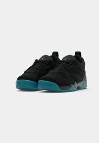 Un paio di scarpe da atletica nere con suole turchesi e loghi Jumpman blu sulle linguette, mostrati affiancati su uno sfondo bianco.