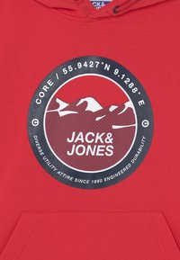 Felpa rossa con cappuccio caratterizzata da un logo circolare con design di montagna, testo "JACK & JONES" e coordinate. Il materiale sembra morbido, probabilmente una miscela di cotone.