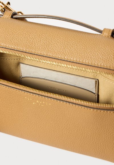 Χειροποίητη τσάντα από ταμπά δέρμα με υφή, ανοιχτή για να αποκαλύψει μια μπεζ δερμάτινη θήκη για κάρτες με ανάγλυφο λογότυπο Tory Burch, χρυσό φερμουάρ και αντίστοιχες λεπτομέρειες στη λαβή.
