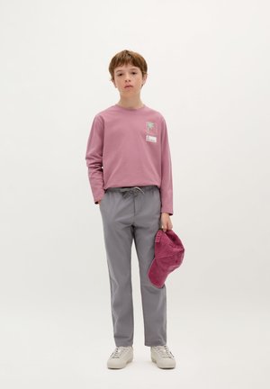Maglietta rosa a maniche lunghe con grafica di palma, pantaloni elasticizzati grigi e cappellino bordeaux. Scarpe da ginnastica bianche con texture leggera. Sfondo semplice.