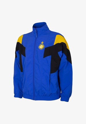 Blauwe zip-up jas met zwarte en gele accenten; heeft een hoge kraag, elastische manchetten en een sportief ontwerp; bevat een logo op de borst.