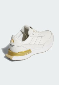 White athletic shoe with textured upper, three stripes on the side, and yellow accent on the sole. Features a cushioned collar and laces.