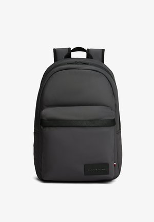 Zwarte Tommy Hilfiger rugzak met gewatteerde bandjes, een voorvak met rits en een logopatch op de rechteronderhoek.