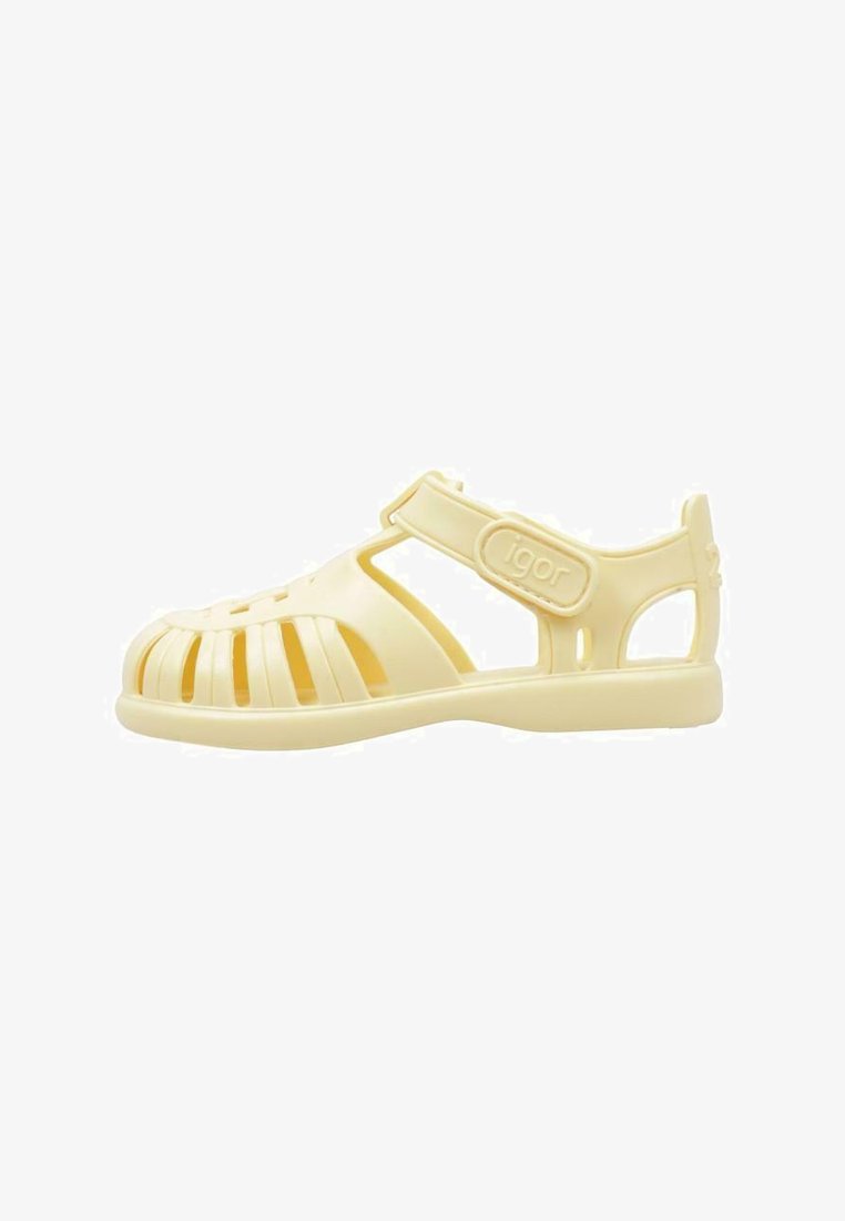 Yellow plastic sandals with a closed toe, slotted upper design for ventilation, adjustable strap, and logo detail on the side.