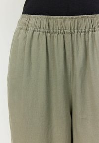 Svijetlo maslinasto zelene tkanine hlače s elastičnom waistbandom, s mekanom teksturom i nabranim detaljima na struku.