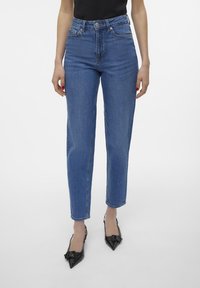 Jeans din denim albastru, cu talie înaltă, cu un croi drept, având un design clasic cu cinci buzunare și fermoar. Finisaj simplu, fără ornamentații.