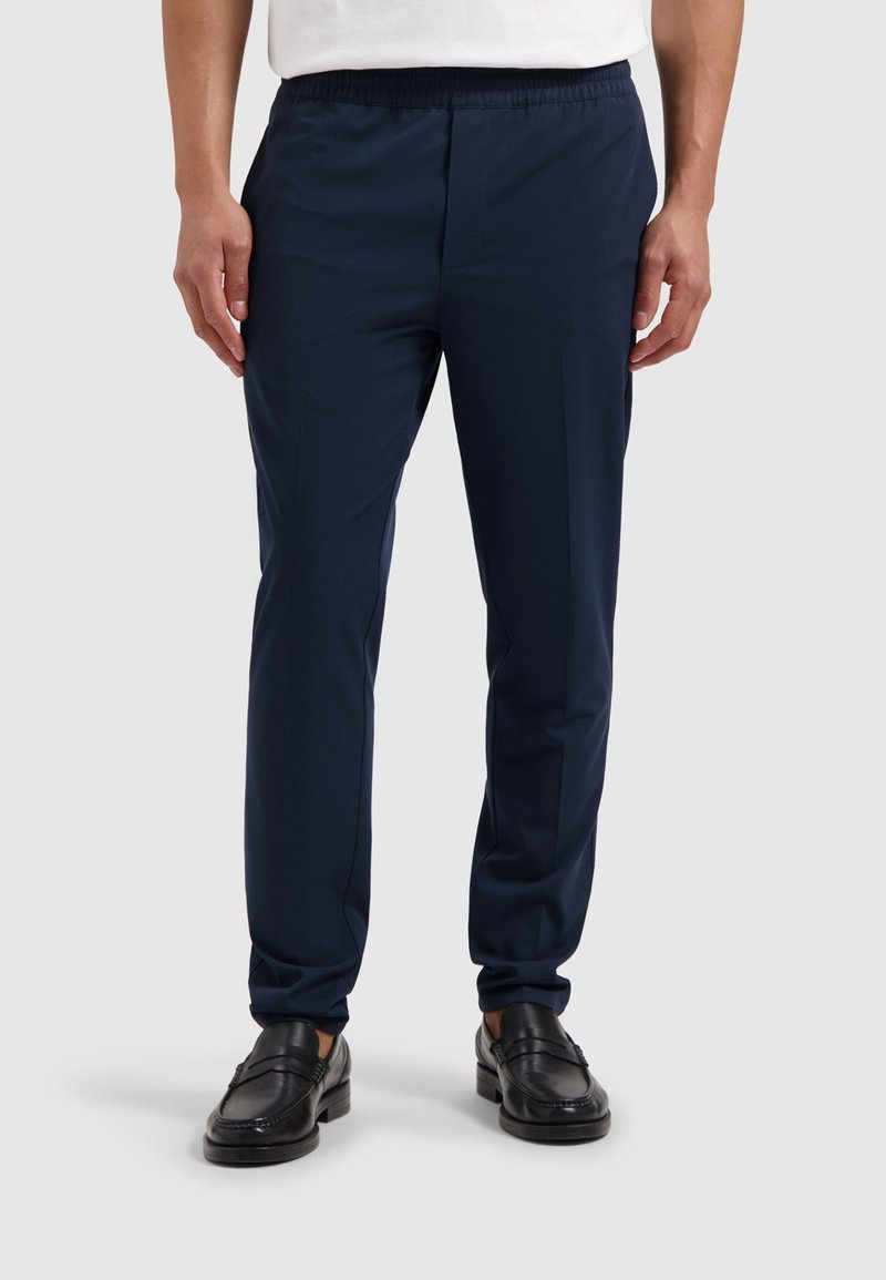 Marineblauwe sportbroek met een elastische tailleband, taps toelopende pasvorm en een gladde textuur. Vergezel je met zwarte instapschoenen voor een casual uitstraling.