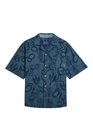 Camicia blu a maniche corte con bottoni, con motivi floreali e foglie astratti scuri e una tasca sul petto su sfondo bianco.