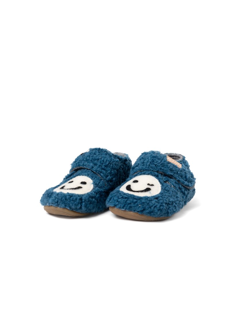 Pantofole blu e pelose con una morbida texture e disegni di faccine sorridenti bianche sul davanti. Presentano una fascia in velcro per una facile vestibilità.