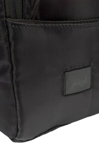 Zaino in tessuto nero con una superficie liscia, dotato di una tasca laterale e un patch del logo cucito. Design semplice senza motivi visibili.