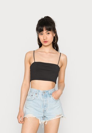 Top cropped preto com alças finas, combinado com calções de ganga claros de cintura alta com bordas desfiadas e um bolso frontal.