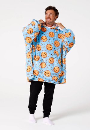 Oversized blue blanket hoodie featuring a pattern of smiling cookies, made of soft fabric, with a kangaroo pocket and cuffed sleeves.