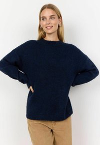 Pulover tricotat de culoare bleu marin, cu guler rotund, croială supradimensionată și mâneci lungi. Textură moale, cu tiv și manșete ribbed. Fundal neutru.