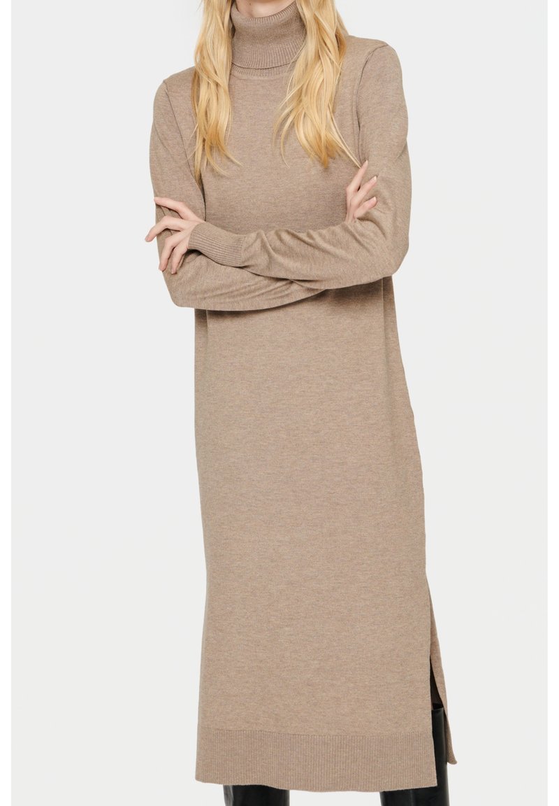 Robe-pull beige à manches longues avec col roulé, fentes latérales, poignets et ourlet côtelés. Texture douce avec une silhouette ajustée.