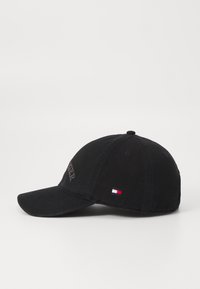 Fekete baseball sapka ívelt karimával, hímzett logóval az elején és egy kis színes zászló címkével az oldalon. Pamut anyag, texturált felülettel.
