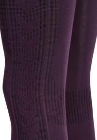 Close-up of purple textured fabric leggings with small perforated patterns forming chevron and linear designs.