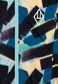 Colorful jacket featuring a blue, black, and yellow abstract pattern with brush strokes, zip closure, and a white logo detail on the chest.